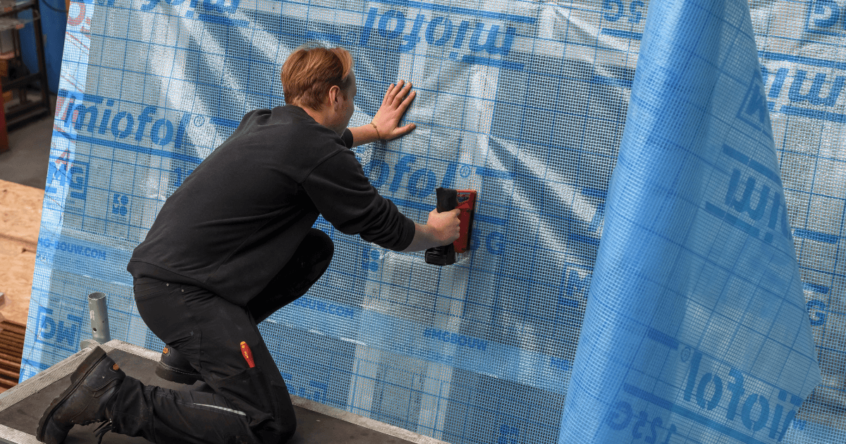 man die folie vastzet aan de buitenkant van het huis